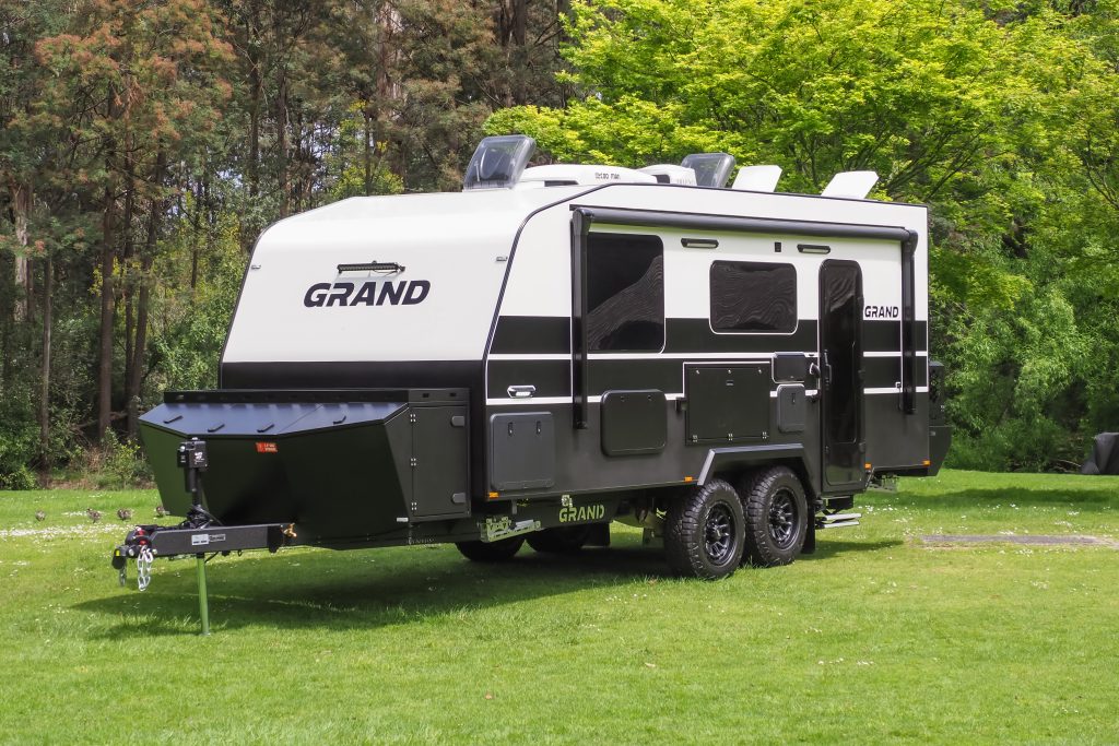 A Grand Caravan parked on the grass in front of an Australian forest